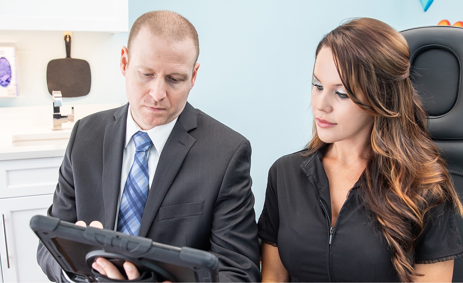 Professionals discussing information on a tablet.