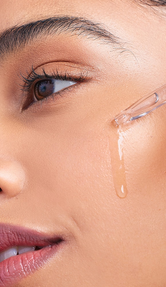 Model applying serum to glowing skin.