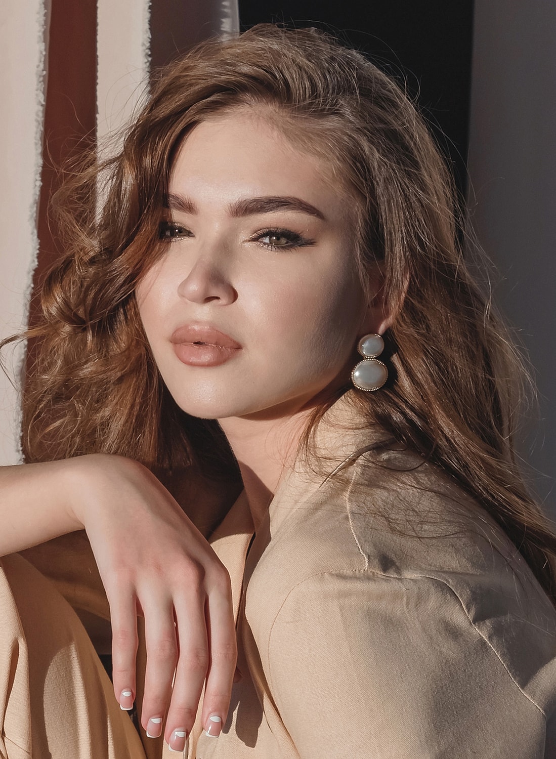 Woman with wavy hair and statement earrings.