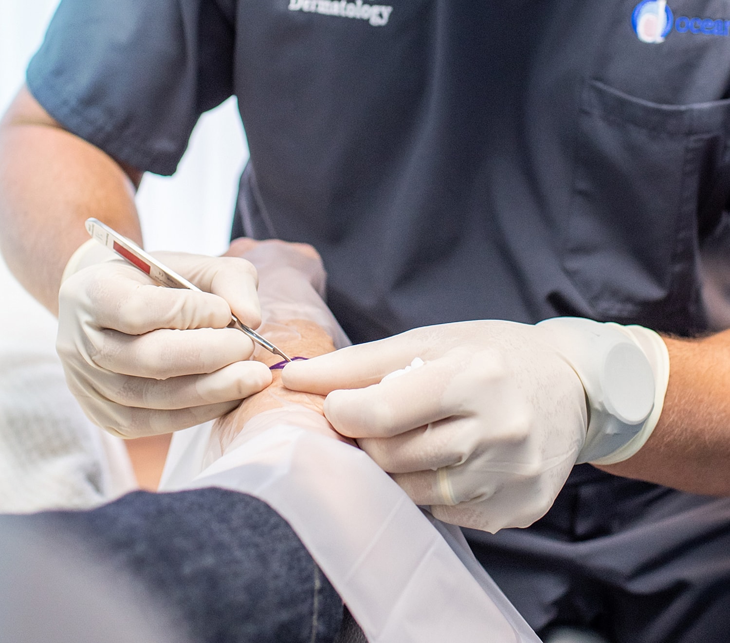 Medical professional performing a procedure on arm.