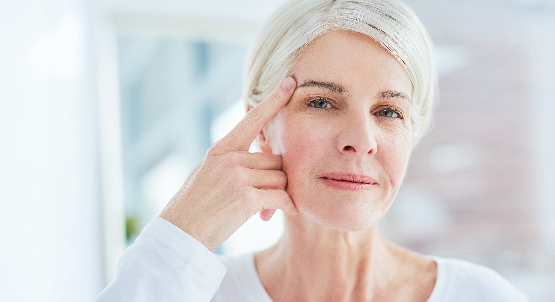 Woman touching her forehead, looking thoughtfully.