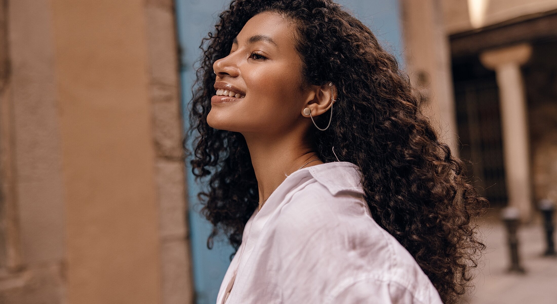 Smiling woman with curly hair outdoors.